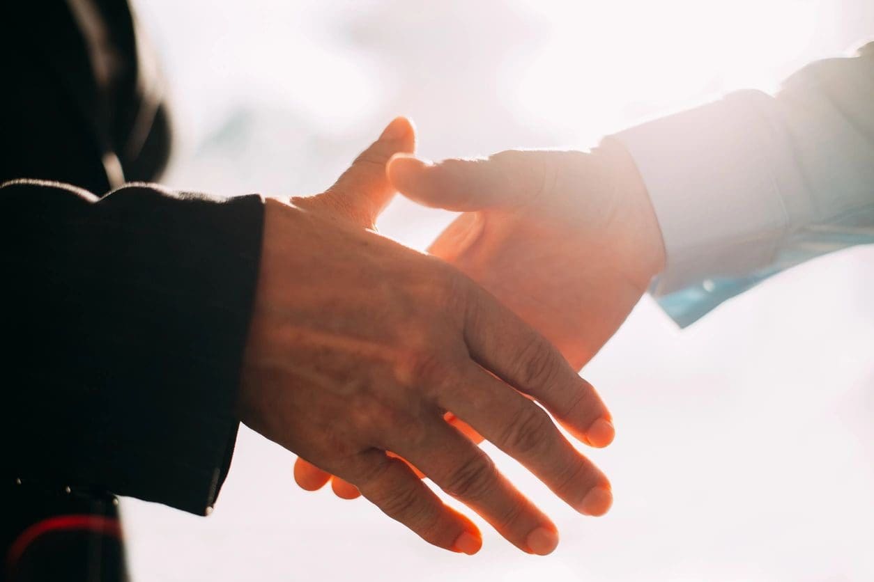 Two people shaking hands in front of a window.